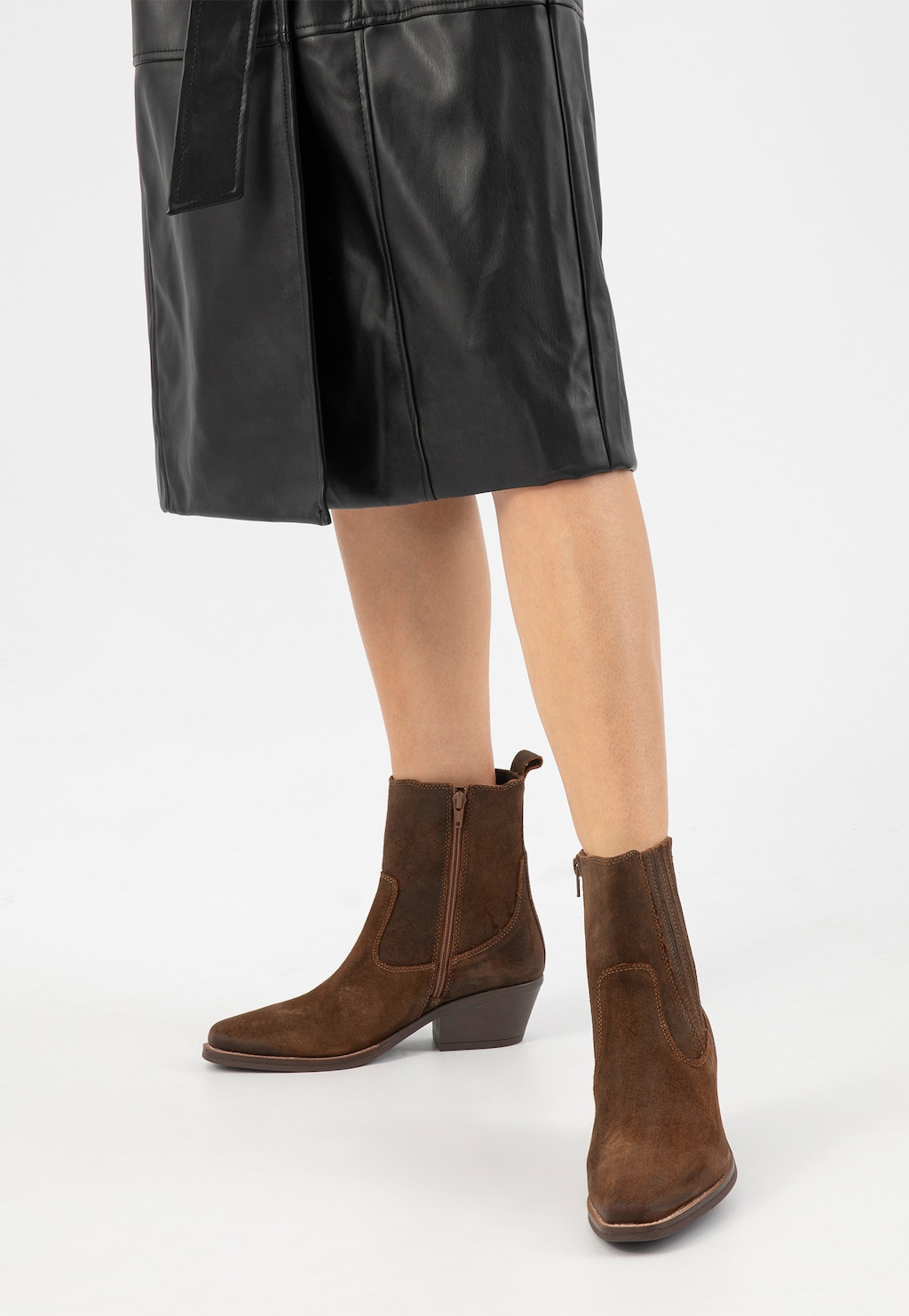 Brązowe botki typu kowbojki Wojas model 55294-62 na niskim obcasie, ze skórzanymi wstawkami i zamkiem bocznym, noszone do czarnej skórzanej spódnicy.