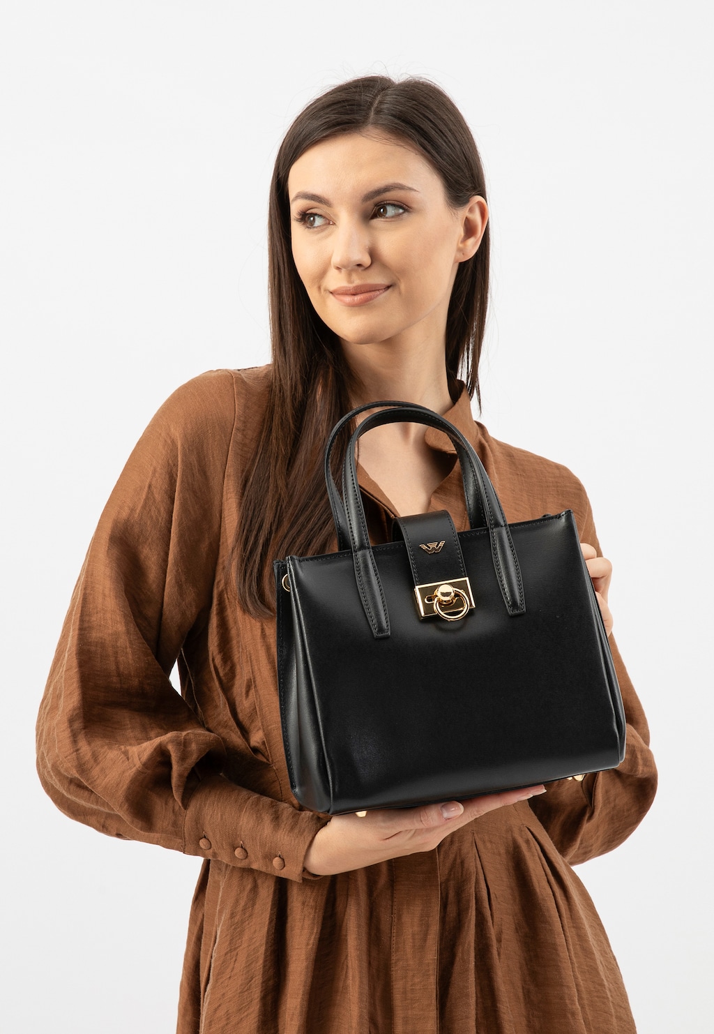 Elegancka czarna torebka Wojas model 80404-51 typu kuferek ze złotym zapięciem, prezentowana w dłoniach modelki ubranej w brązową sukienkę.