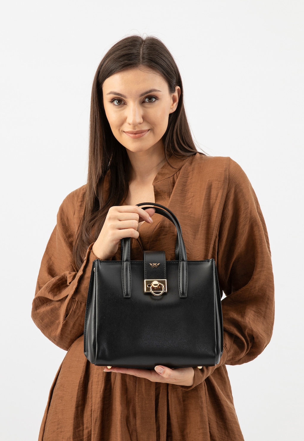 Czarna elegancka torebka damska Wojas model 80404-51 typu kuferek ze złotym zapięciem, prezentowana w rękach modelki ubranej w brązową sukienkę.