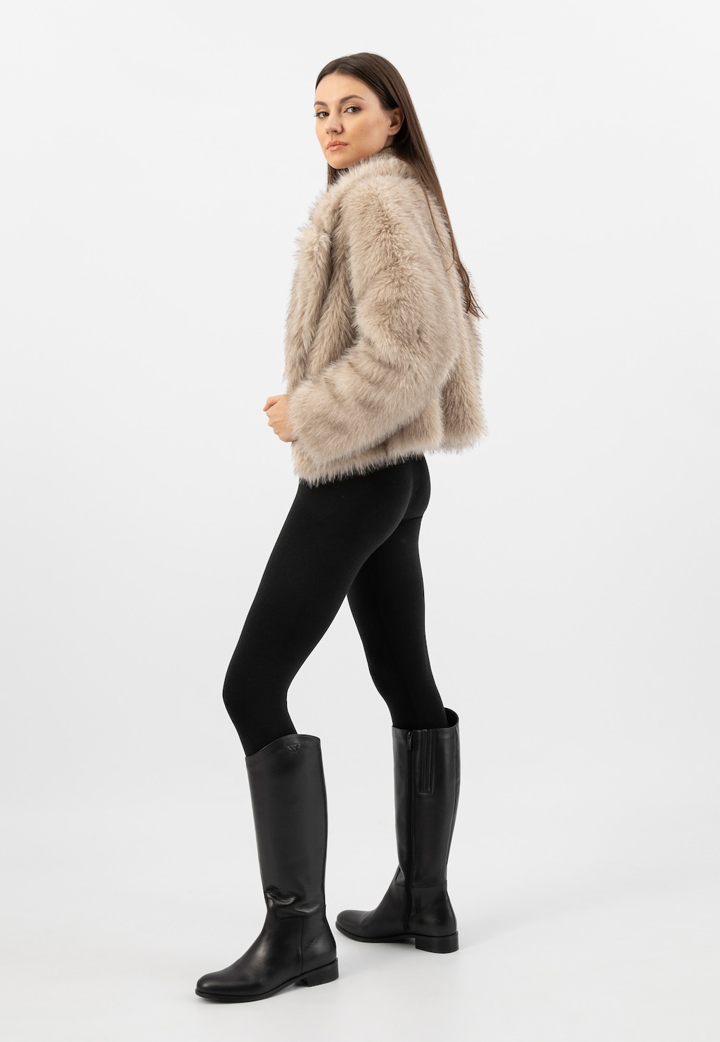 Modelka w beżowym futerku i czarnych legginsach prezentująca czarne skórzane kozaki damskie Wojas z ociepleniem model 71070-51, widok z profilu.