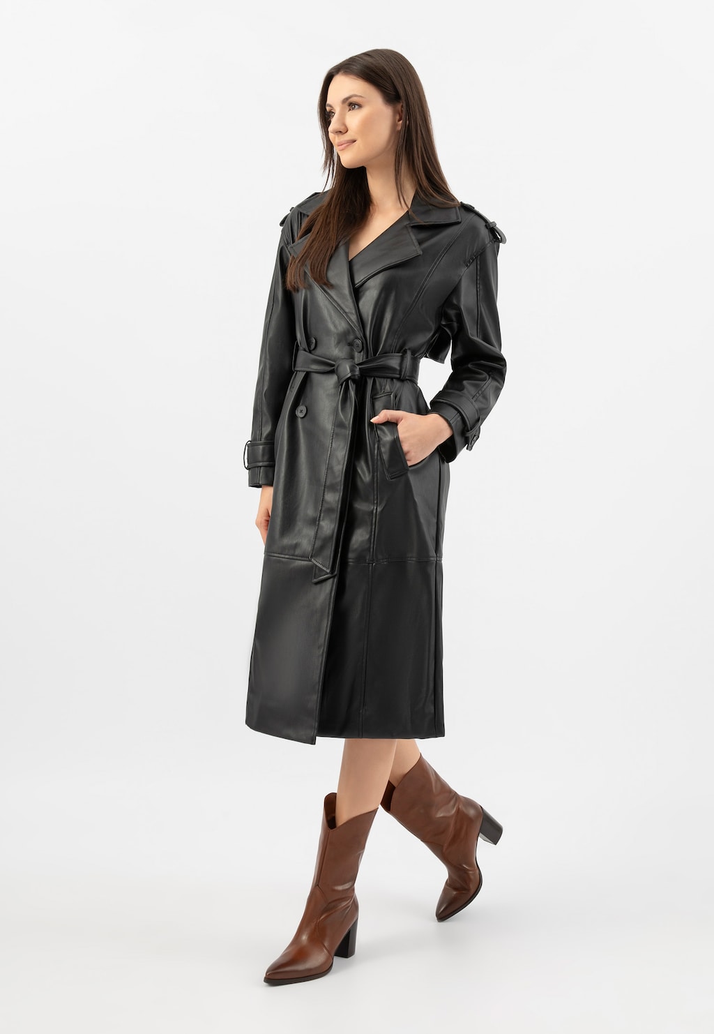 Modelka w czarnym płaszczu skórzanym z paskiem, prezentująca brązowe kowbojki damskie Wojas model 55239-52 na obcasie, wykonane ze skóry naturalnej.