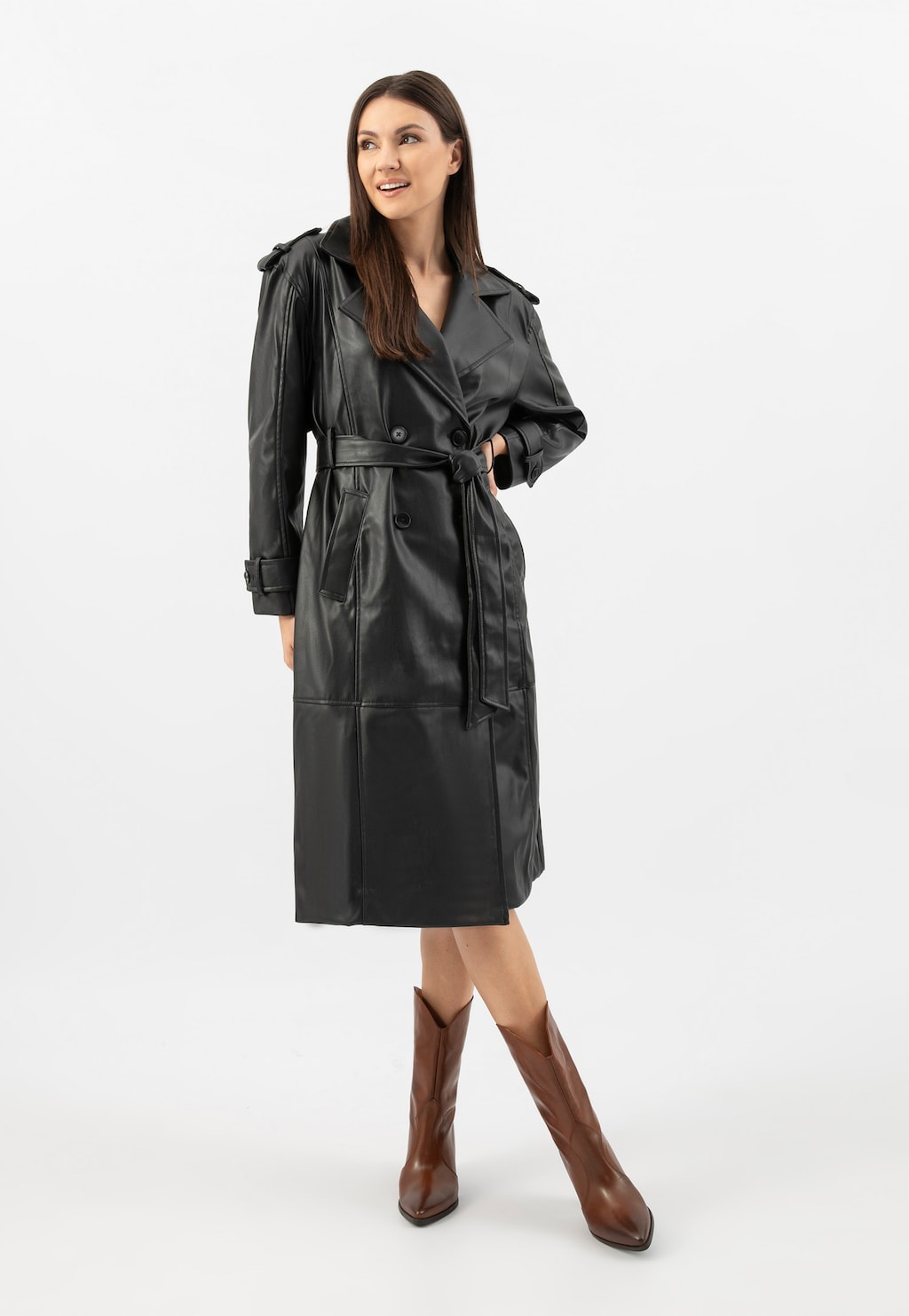 Modelka w czarnym płaszczu skórzanym prezentująca brązowe kowbojki damskie Wojas model 55239-52 na obcasie. Stylowy zestaw na chłodniejsze dni.