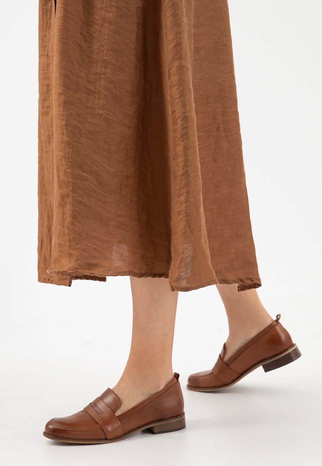 Eleganckie jasnobrązowe mokasyny damskie Wojas 46004-53 ze skóry licowej, ukazane na nogach kobiety w brązowej lnianej spódnicy, widok z profilu.