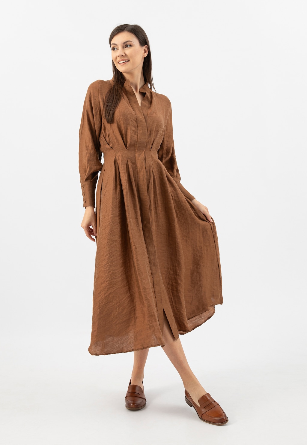 Modelka w brązowej sukience prezentuje jasnobrązowe mokasyny damskie Wojas ze skóry licowej model 46004-53, eksponując ich elegancki wygląd i dopasowanie do stylizacji.