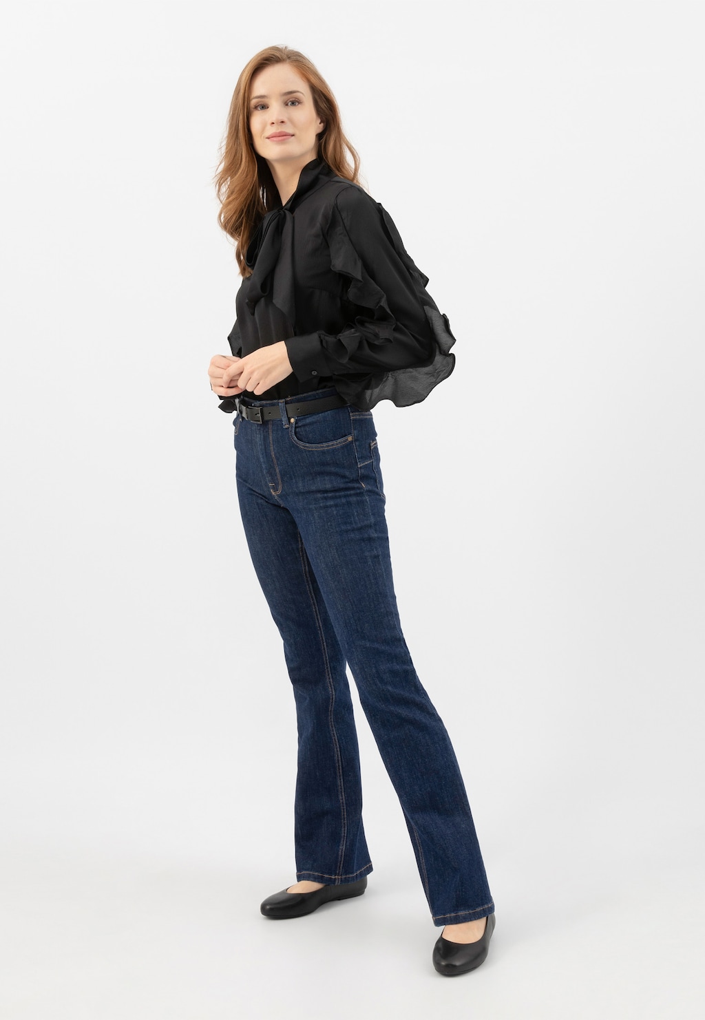 Modelka w eleganckim stroju z czarną bluzką i jeansami, prezentująca czarne klasyczne baleriny Wojas model 44024-51 ze skóry licowej.