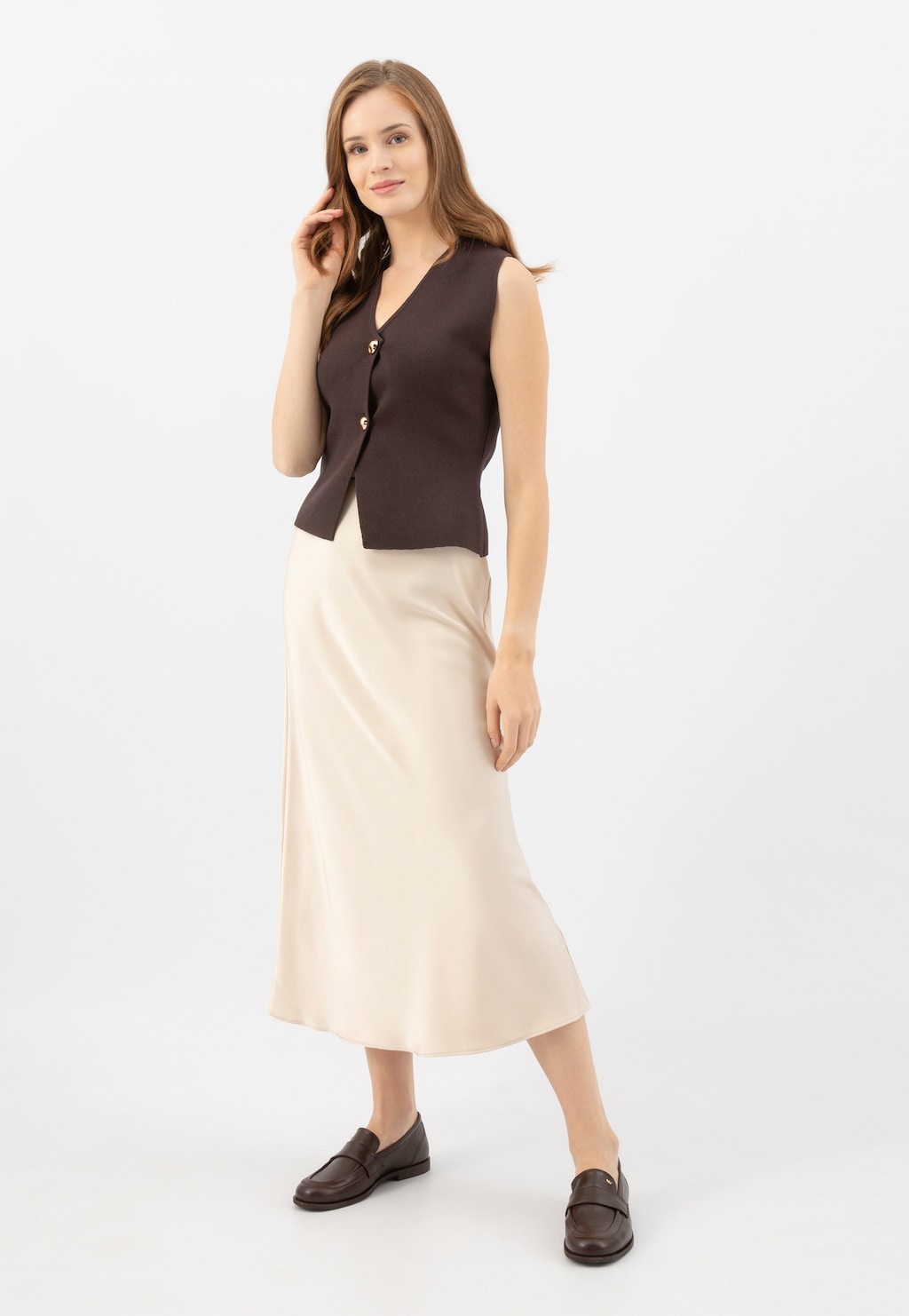 Modelka w eleganckim stroju z jasną spódnicą i brązową kamizelką, prezentująca brązowe mokasyny damskie Wojas 46314-52 ze skóry naturalnej, idealne do biznesowych stylizacji.
