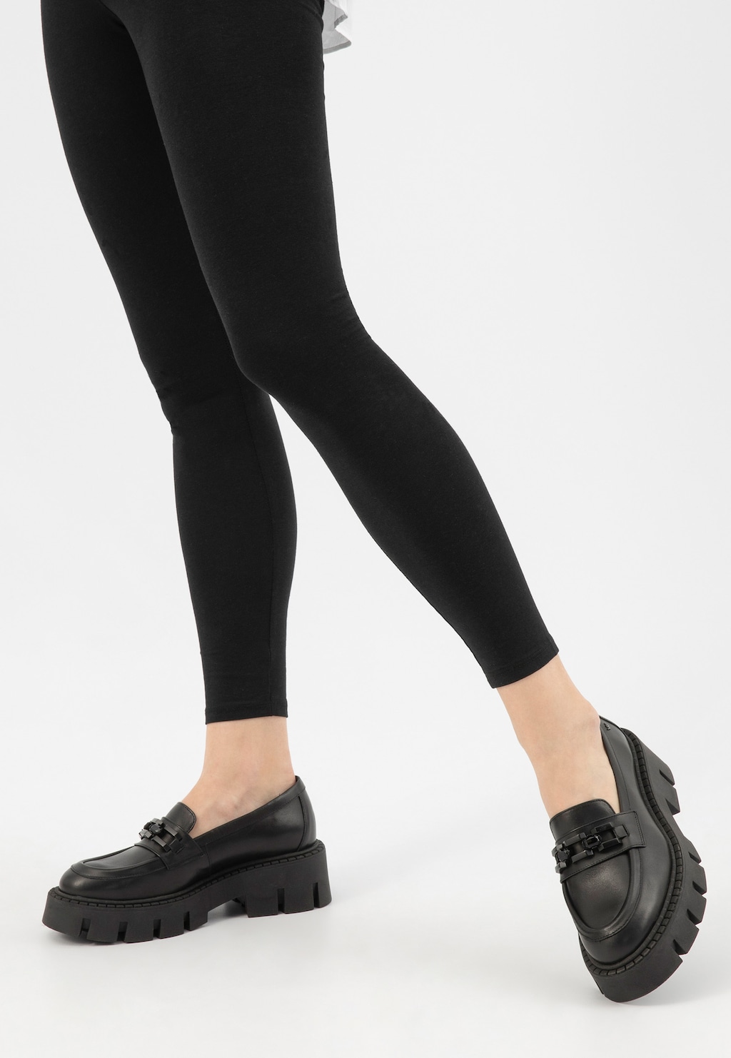 Masywne mokasyny Wojas model 46317-51 z czarnym łańcuchem na grubej podeszwie, prezentowane na nogach w czarnych legginsach. Stylowe buty o wyrazistym charakterze.