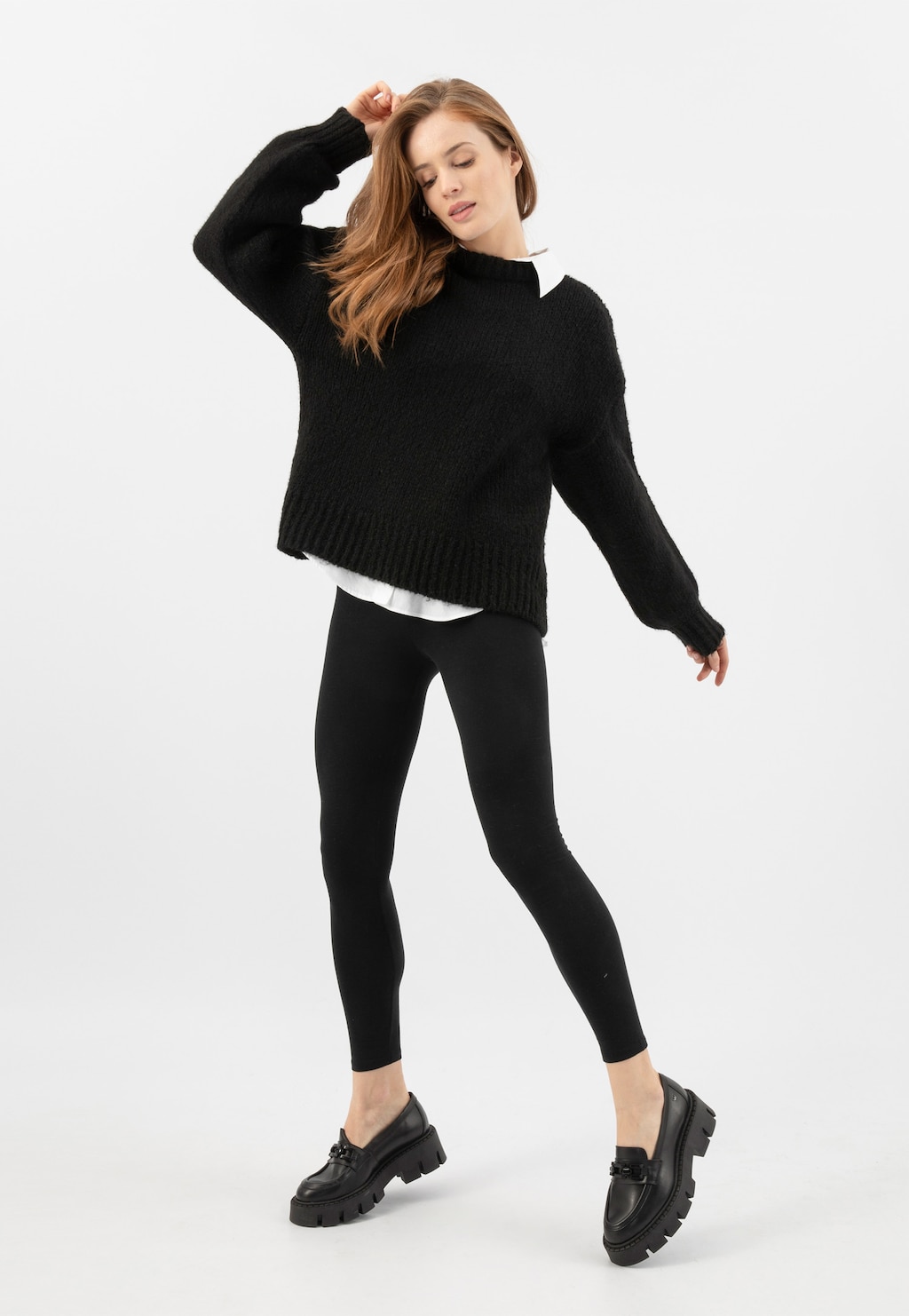 Modelka w czarnym swetrze i legginsach prezentuje masywne mokasyny Wojas model 46317-51 z czarnym łańcuchem na grubej podeszwie, idealne do stylizacji casual.