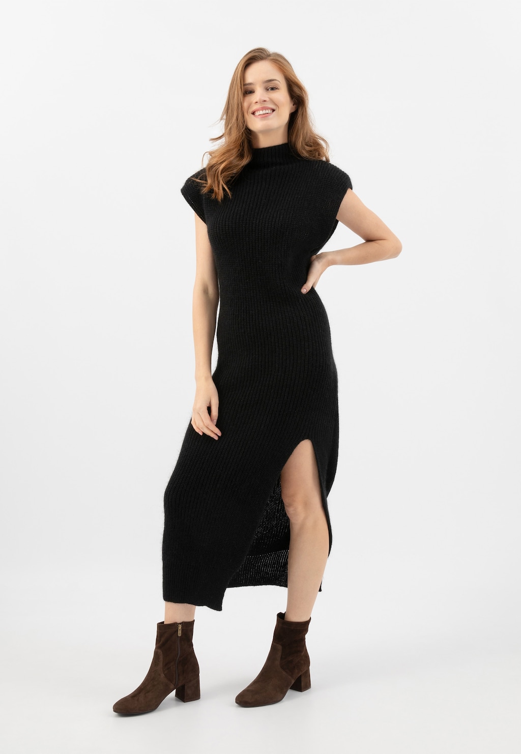 Elegancka czarna sukienka dzianinowa z rozcięciem, uzupełniona brązowymi botkami Wojas model 55094-62 na niskim obcasie, idealne na jesień.