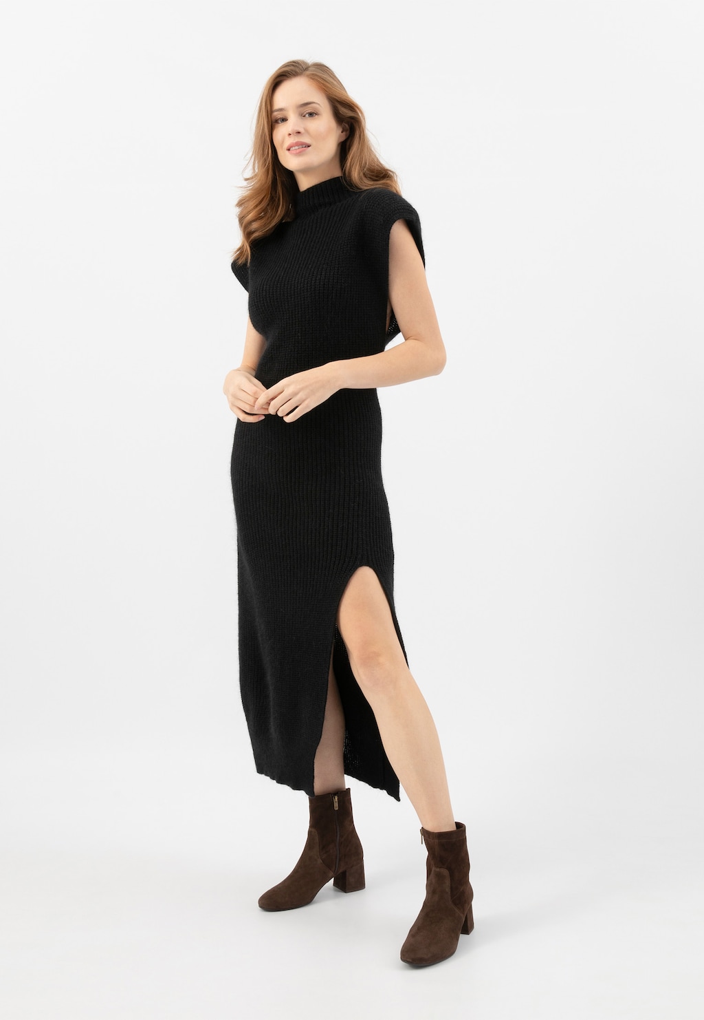 Osoba w czarnej sukience z rozcięciem prezentująca brązowe botki Wojas model 55094-62 na niskim obcasie, idealne na jesień.