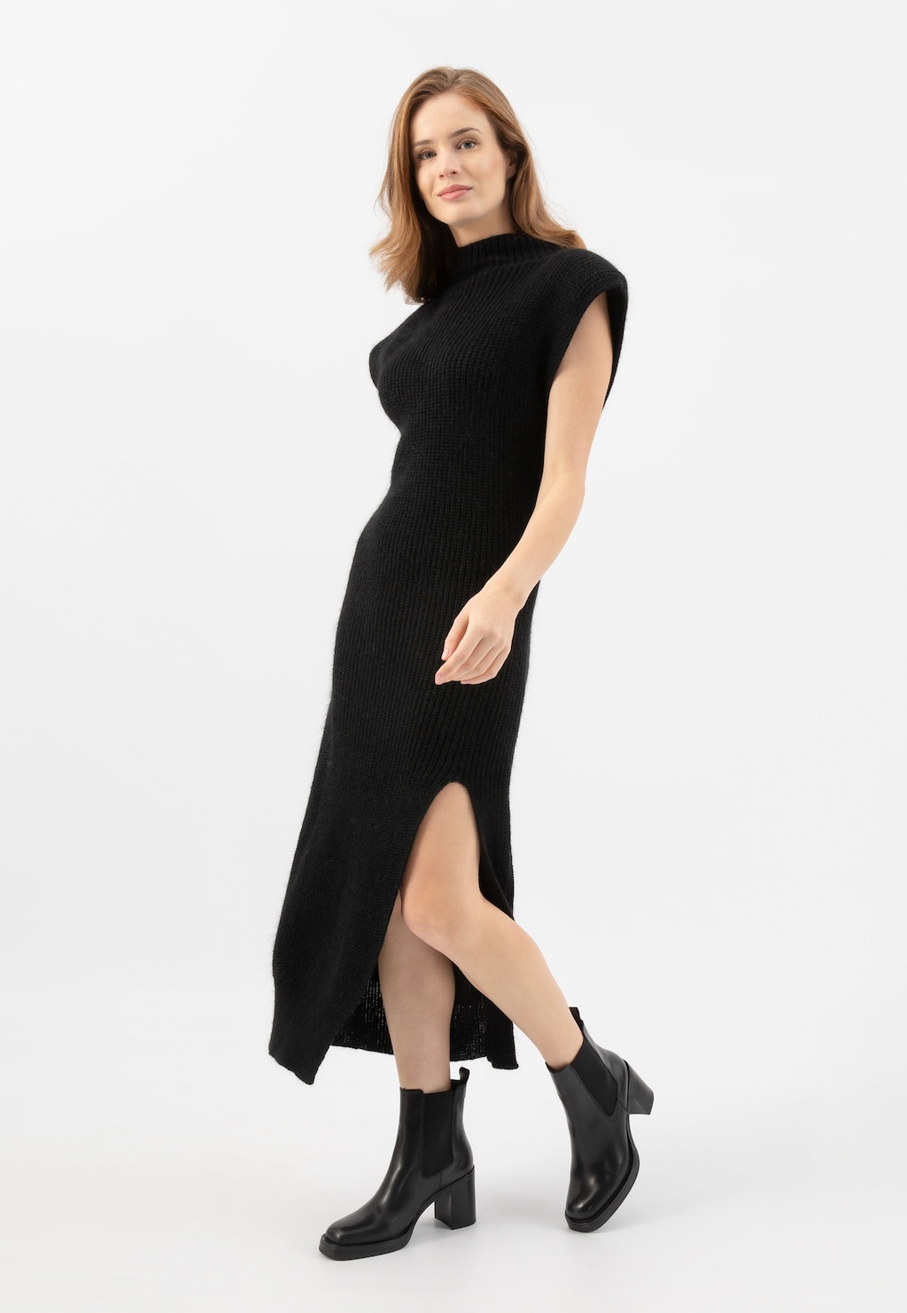 Modelka w czarnej sukience z rozcięciem prezentująca eleganckie czarne botki Wojas model 55260-51 na stabilnym obcasie, doskonałe jako klasyczne obuwie na różne okazje.
