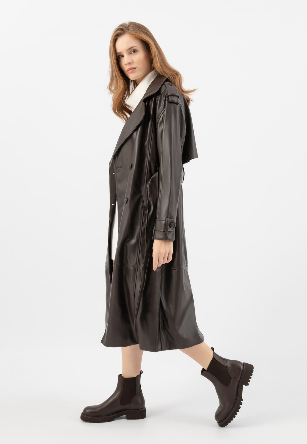 Model w długim skórzanym płaszczu prezentuje brązowe masywne sztyblety damskie Wojas 55266-52 ze skóry licowej. Buty mają charakterystyczną elastyczną wstawkę i grubą podeszwę.