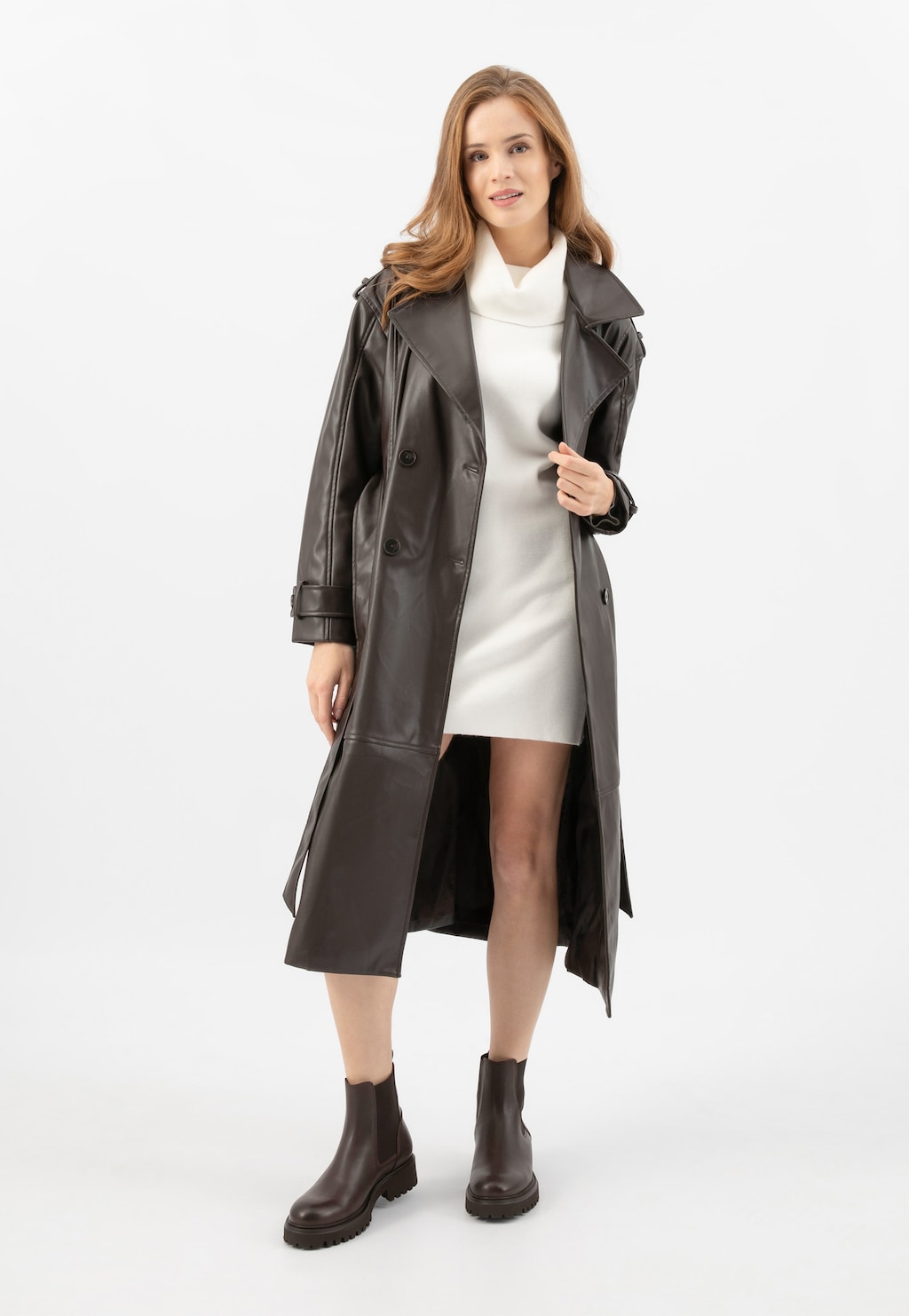 Modelka w brązowym płaszczu i białej sukience prezentuje brązowe masywne sztyblety damskie Wojas ze skóry licowej model 55266-52 na grubej podeszwie.