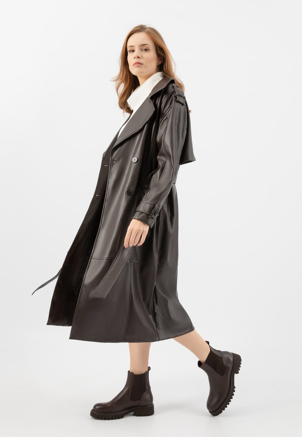 Modelka w czarnym płaszczu skórzanym prezentująca brązowe masywne sztyblety damskie Wojas ze skóry licowej model 55266-52 na grubej, profilowanej podeszwie.