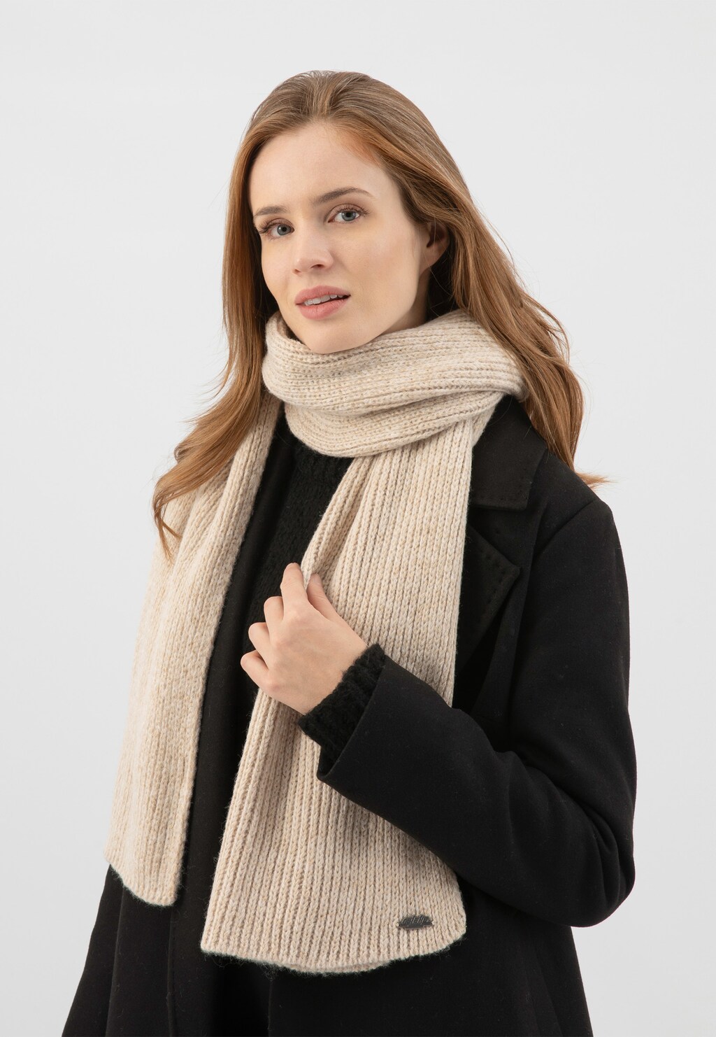 Jasnobeżowy szalik RELAKS model R96030-84 z wiskozą i złotą nitką, elegancko owinięty wokół szyi osoby w czarnym płaszczu, podkreślający zimowy styl.