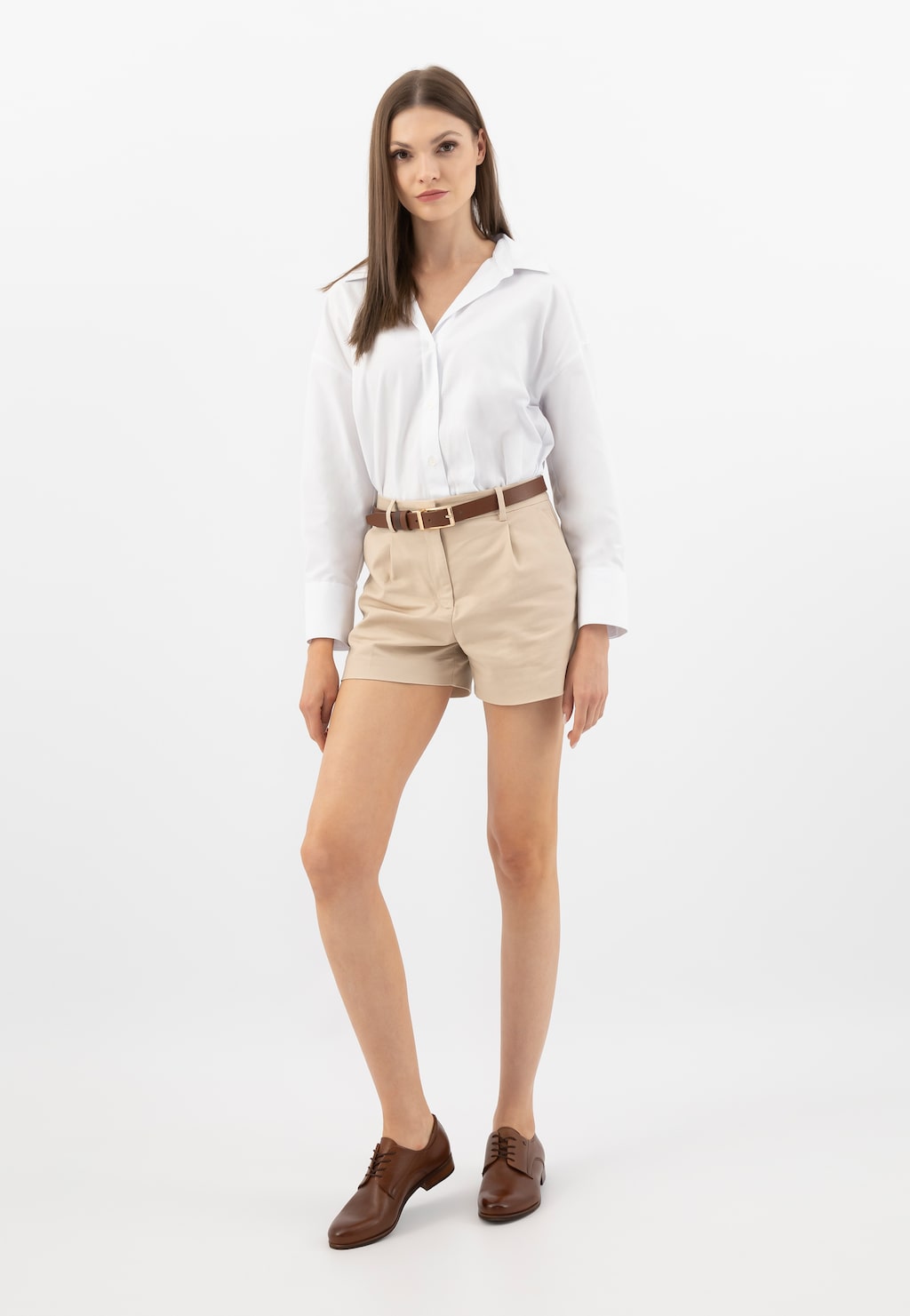Modelka w białej koszuli i beżowych szortach prezentuje brązowe sznurowane półbuty damskie Wojas model 6462-52 ze skóry licowej, idealne do eleganckiej letniej stylizacji.