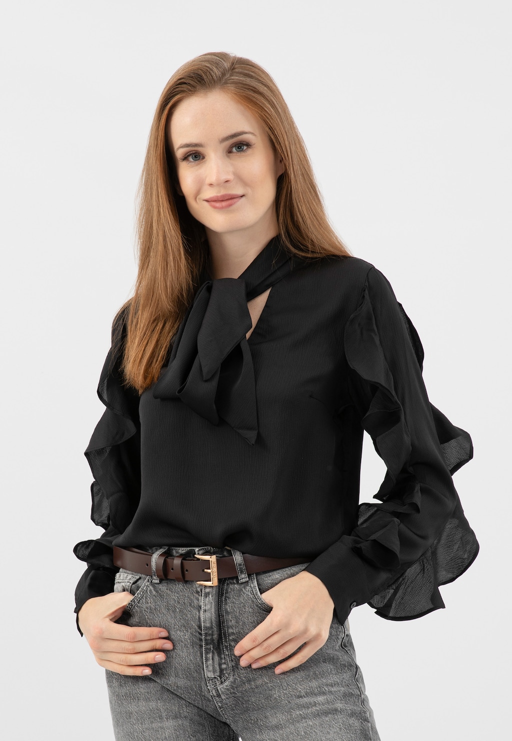 Modelka w czarnej bluzce z kokardą, szarych jeansach z ciemnobrązowym paskiem damskim Wojas model 93084-53 ze złotą klamrą.