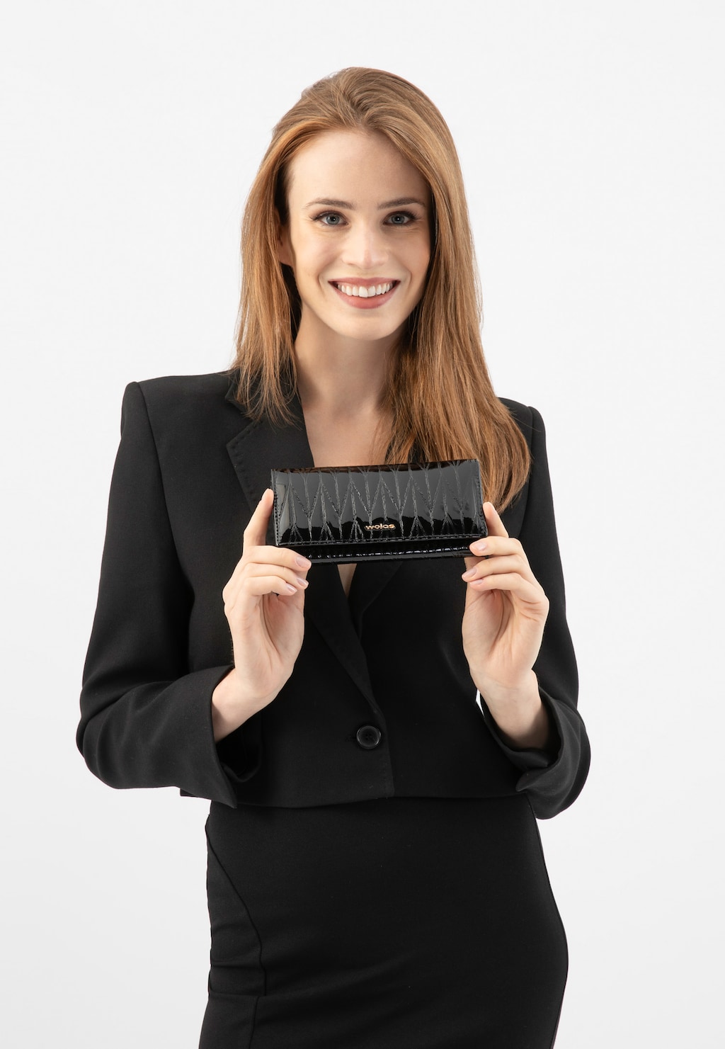 Elegancki czarny lakierowany portfel damski Wojas model 91087-31 trzymany przez osobę w czarnym garniturze. Widoczny pikowany wzór na powierzchni portfela.