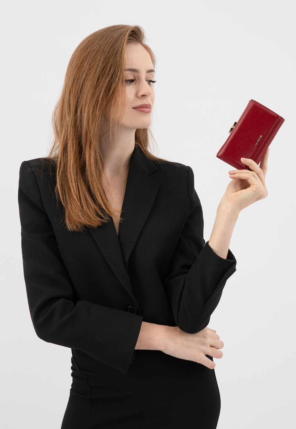 Elegancka osoba w czarnym stroju prezentująca czerwony skórzany portfel damski Wojas model 91085-55 z zapięciem na zatrzask, idealny dodatek do biznesowej stylizacji.
