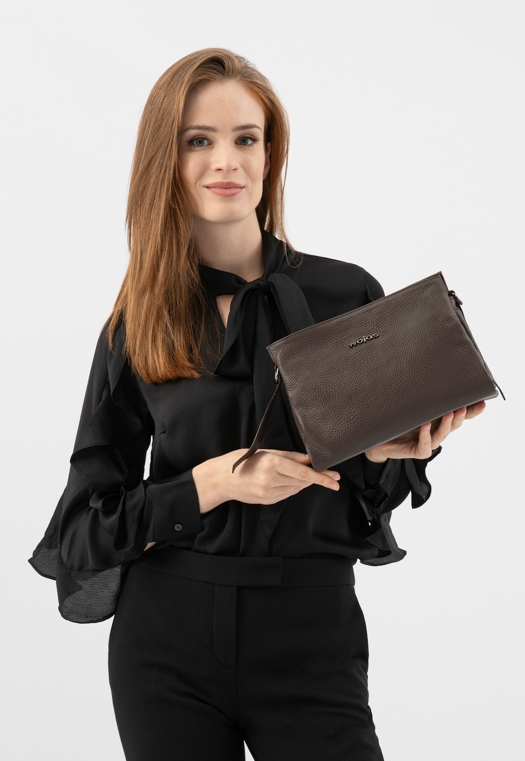 Elegancka osoba w czarnej bluzce prezentująca ciemnobrązową skórzaną torebkę damską Wojas model 80417-52, praktyczną na ramię z widocznym logo marki.