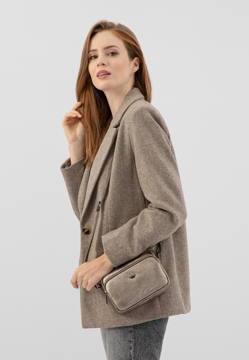 Elegancka złota torebka Wojas model 80317-58 typu crossbody bag na ramieniu osoby w beżowym płaszczu. Kompaktowy rozmiar idealny do codziennych stylizacji.