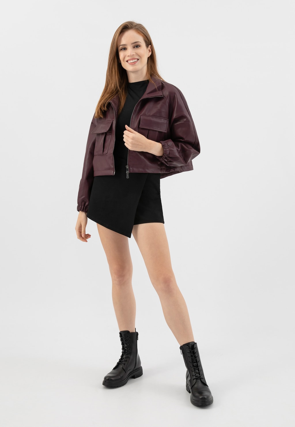 Modelka w bordowej kurtce i czarnej sukience prezentuje czarne skórzane trzewiki damskie Wojas model 64026-59 z ociepleniem, idealne na jesienno-zimowe stylizacje.