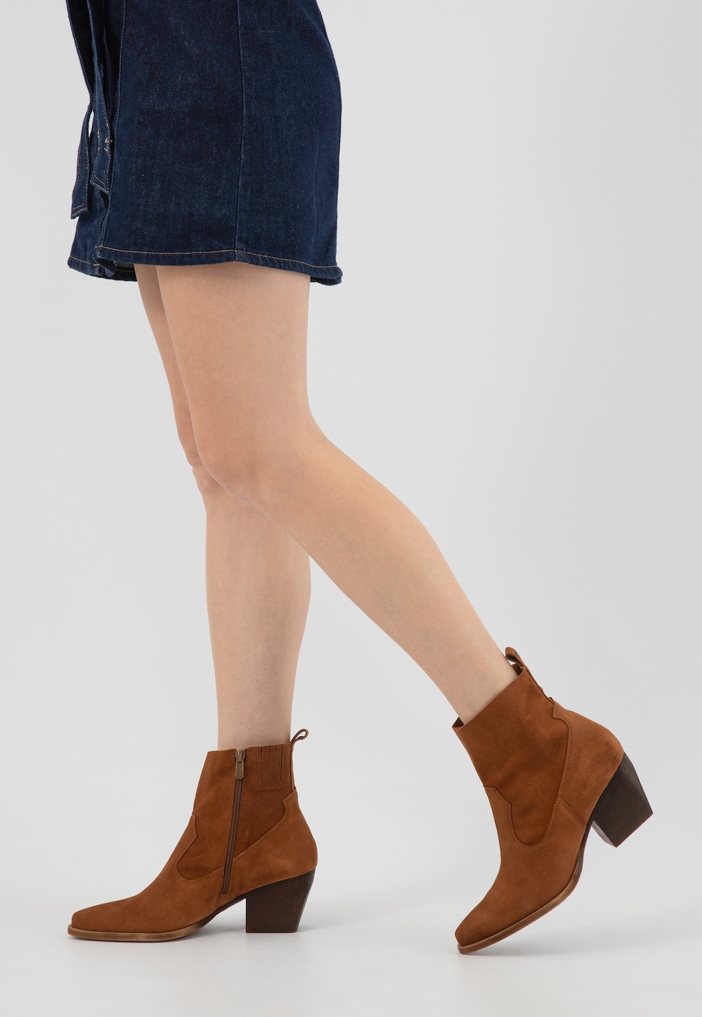 Brązowe kowbojki damskie Wojas model 55247-62 z ozdobnymi przeszyciami, widoczne na nogach osoby noszącej jeansową spódniczkę, na średnim obcasie z bocznym zamkiem.