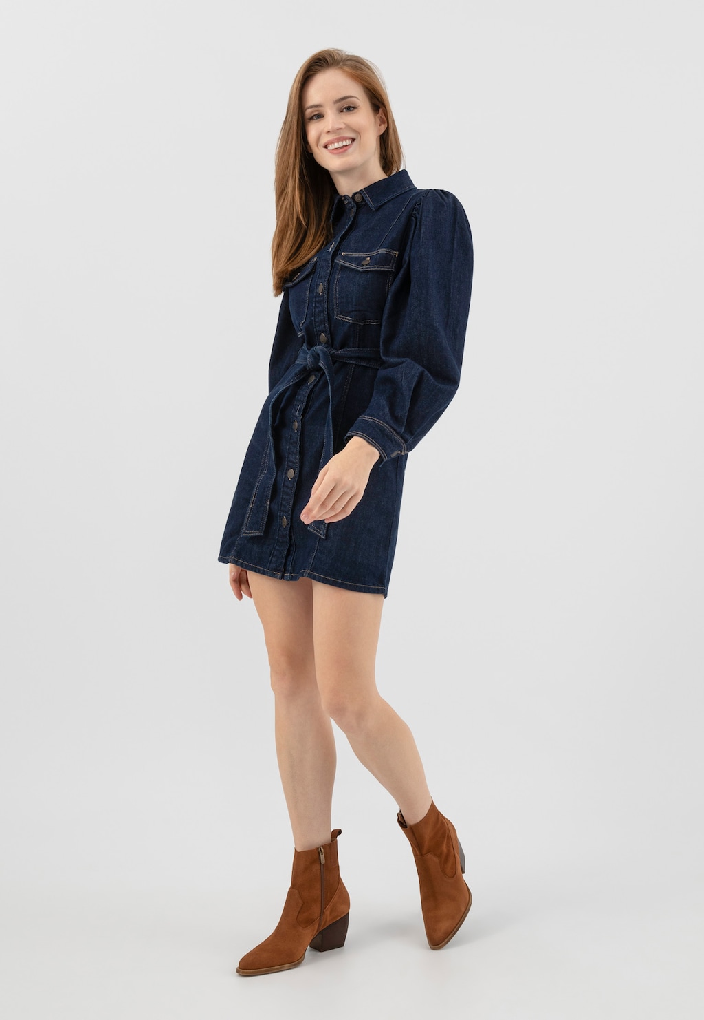 Osoba w jeansowej sukience z paskiem, prezentująca brązowe kowbojki damskie Wojas model 55247-62 z ozdobnymi przeszyciami, idealnie dopełniające casualową stylizację.