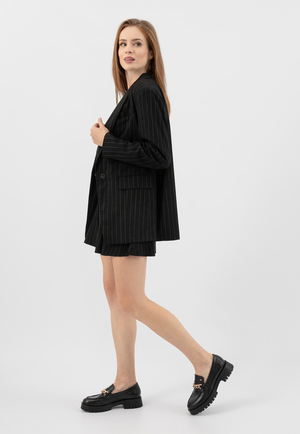 Elegancki czarny garnitur w paski zestawiony z modnymi mokasynami Wojas model 46323-51 ze złotą ozdobą. Stylizacja biznesowa podkreślona czarnymi butami ze skóry licowej.