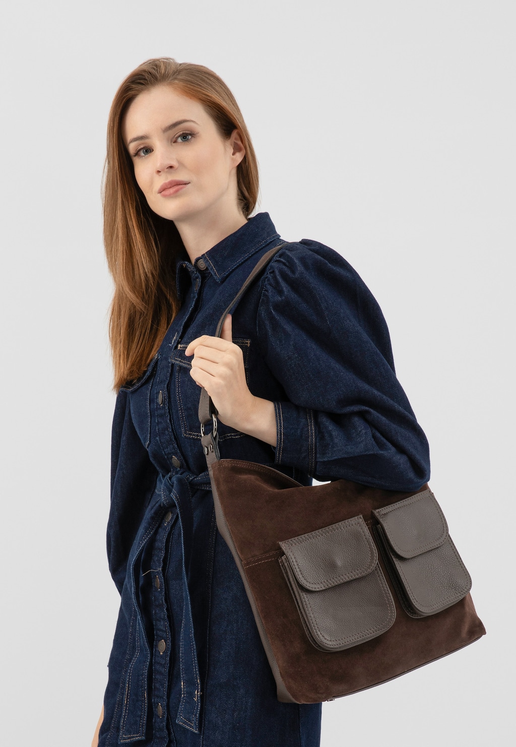 Modelka w jeansowej sukience prezentująca ciemnobrązową torebkę skórzaną damską Wojas model 9819-73 z charakterystycznymi kieszeniami zewnętrznymi i regulowanym paskiem na ramię.