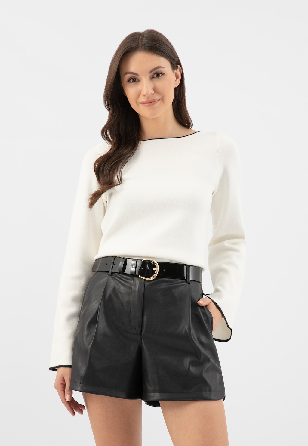 Elegancka stylizacja z czarnym paskiem lakierowanym Wojas 93088-31, dopełniającym biały sweter i czarne skórzane szorty. Pasek ze złotą klamrą podkreśla modny zestaw.