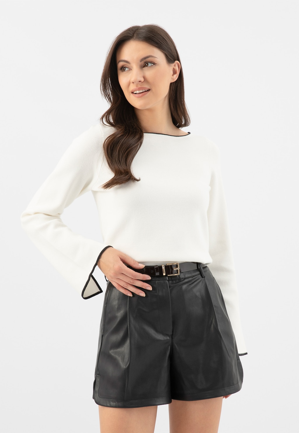 Modelka w białej bluzce i skórzanych szortach, prezentująca bordowy lakierowany pasek damski Wojas model 9961-35 na czarnym pasku z elegancką klamrą.