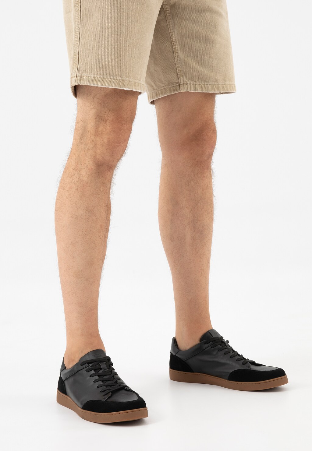 Czarne trampki Wojas model 10217-51 z łączonych skór na brązowej podeszwie, noszone do beżowych szortów, prezentowane na nogach.