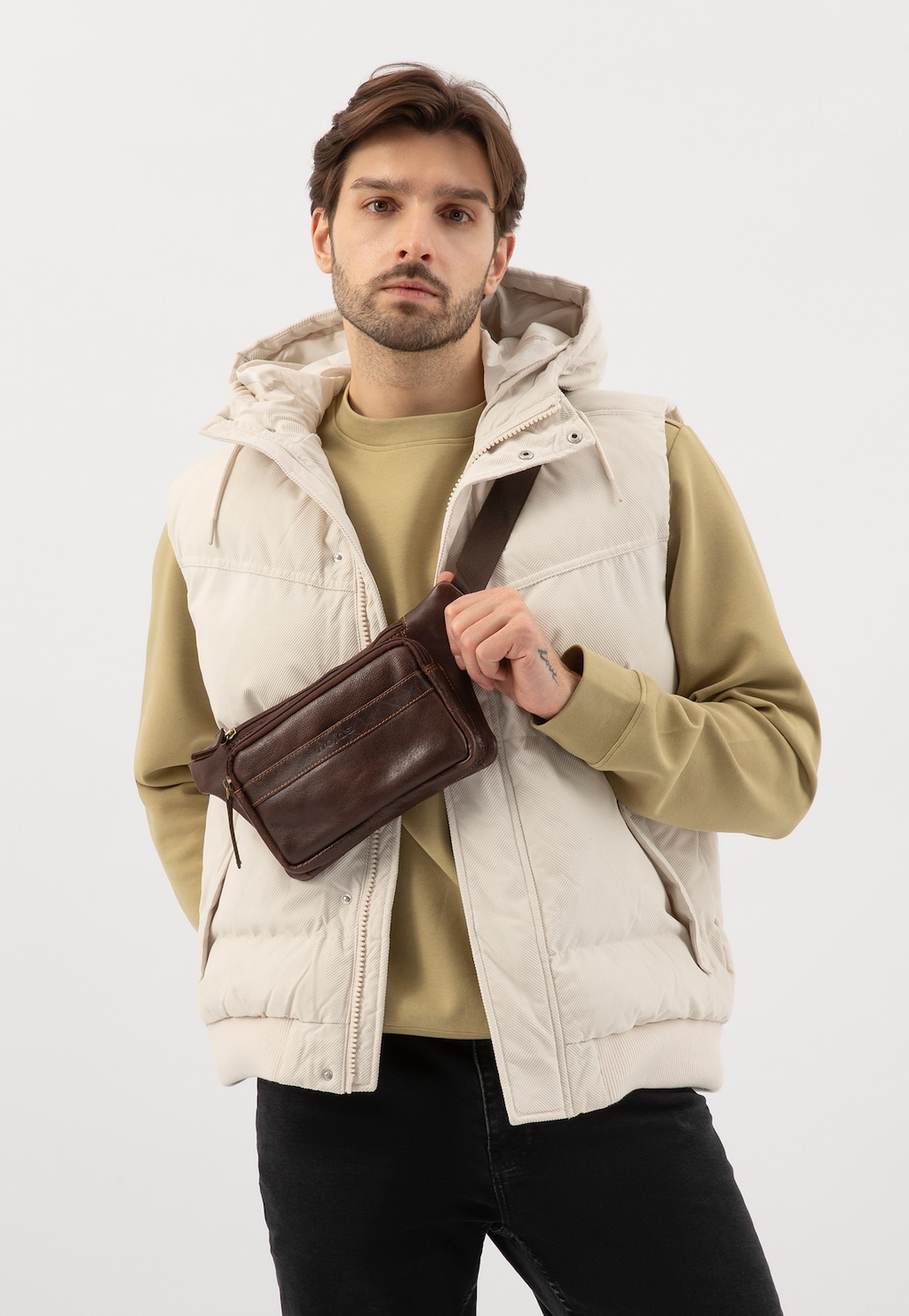 Skórzana brązowa nerka męska Wojas model 90022-52 prezentowana na modelu w kremowej kamizelce z kapturem i beżowej bluzie, noszona jako saszetka przez ramię.