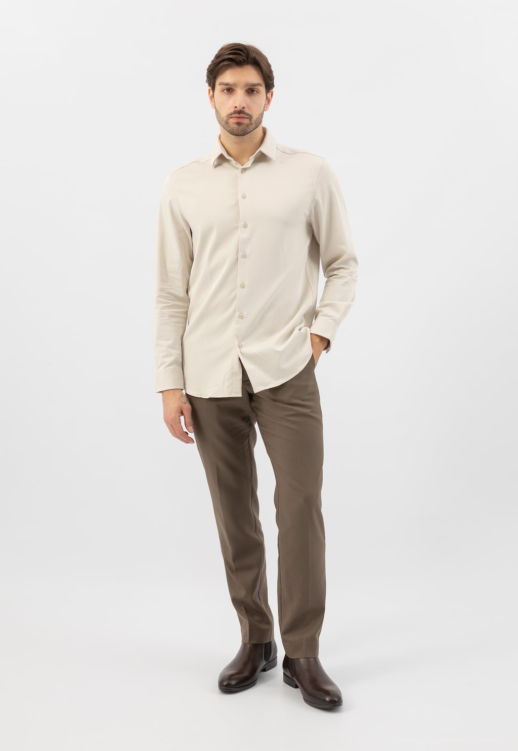 Model prezentujący ciemnobrązowe botki męskie Wojas 20041-52 ze skóry licowej, ubrany w elegancką kremową koszulę i brązowe spodnie, w pełnej stylizacji.