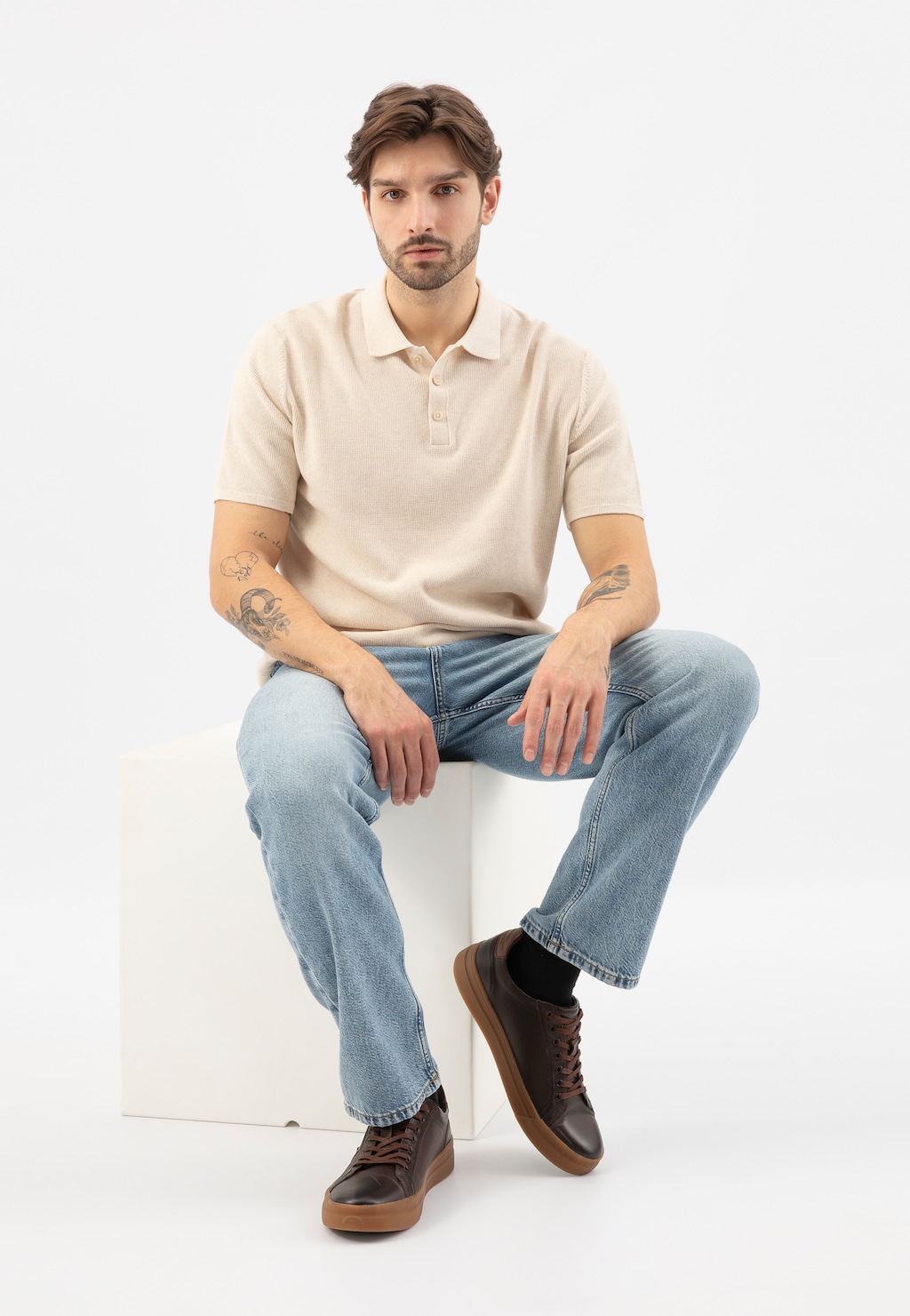 Stylizacja z brązowymi trampkami męskimi Wojas model 10228-52 z jaśniejszymi wstawkami, jasnym polo i jeansami, prezentująca obuwie na gumowej podeszwie.