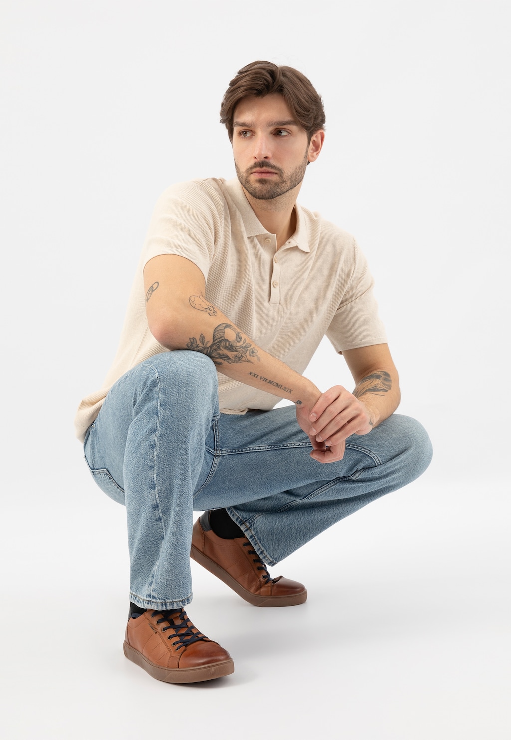 Osoba w beżowej koszulce polo i jeansach, prezentująca brązowe trampki Wojas model 10222-53 z ciemnymi wstawkami. Buty widoczne w casualowej stylizacji.