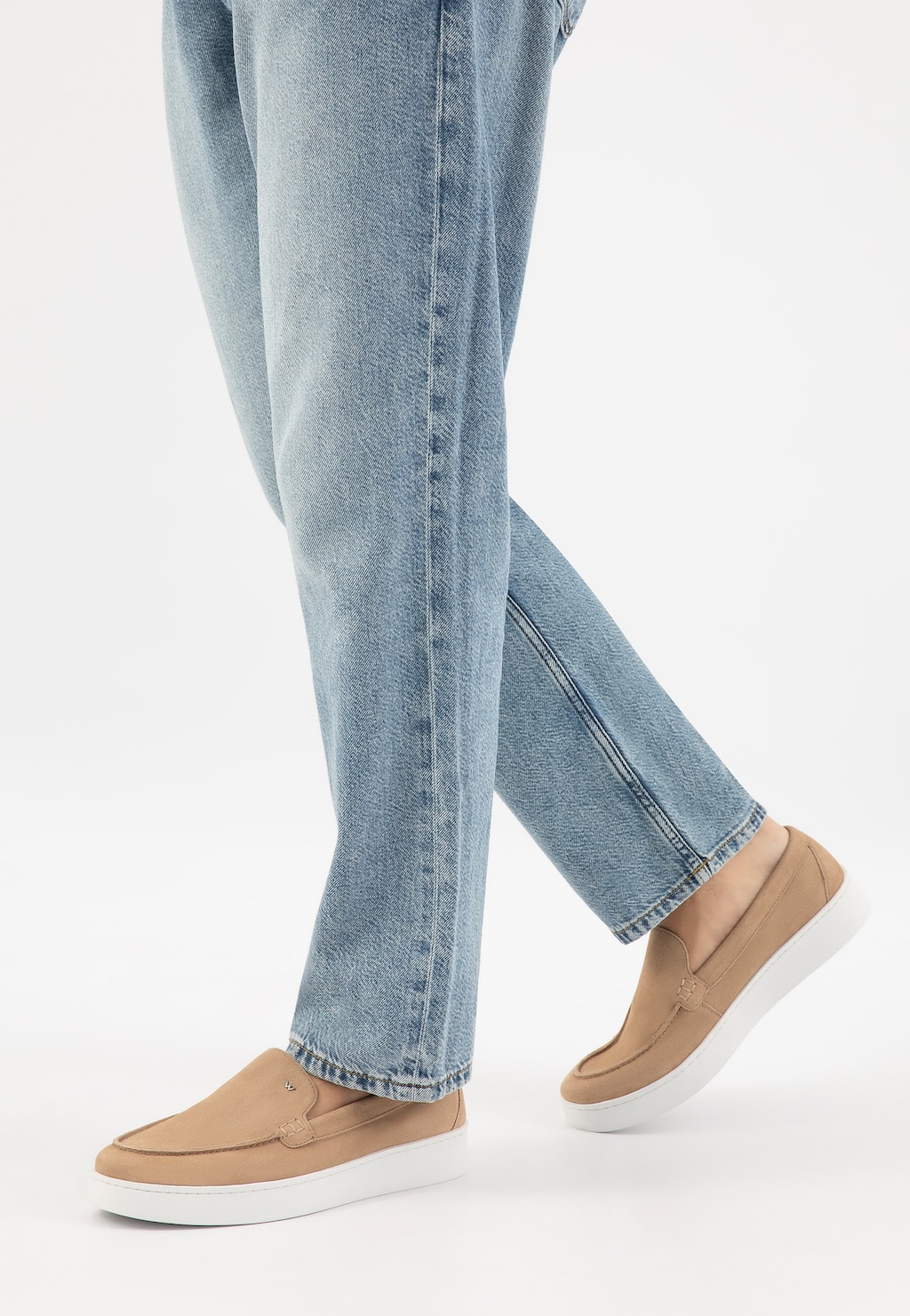 Beżowe mokasyny męskie Wojas model 10218-64 na białej podeszwie, noszone z jasnymi jeansami. Ujęcie z boku pokazujące elegancki, casualowy styl obuwia.