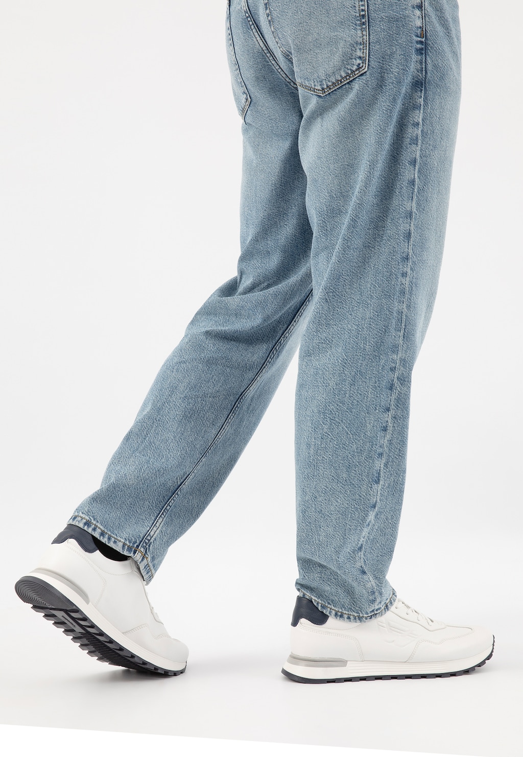 Białe sneakersy męskie Wojas model 10201-50 na kontrastowej czarnej podeszwie, widoczne z boku na nogach w jasnoniebieskich jeansach, podkreślające sportowy, casualowy styl.