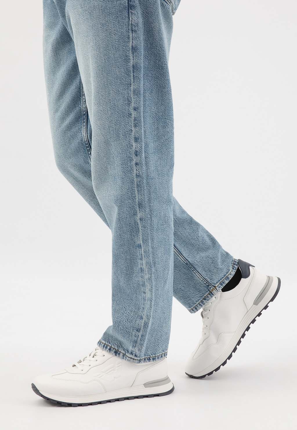 Białe sneakersy męskie Wojas 10201-50 na kontrastowej podeszwie w stylizacji z jasnymi jeansami, widoczne z boku podczas chodu.