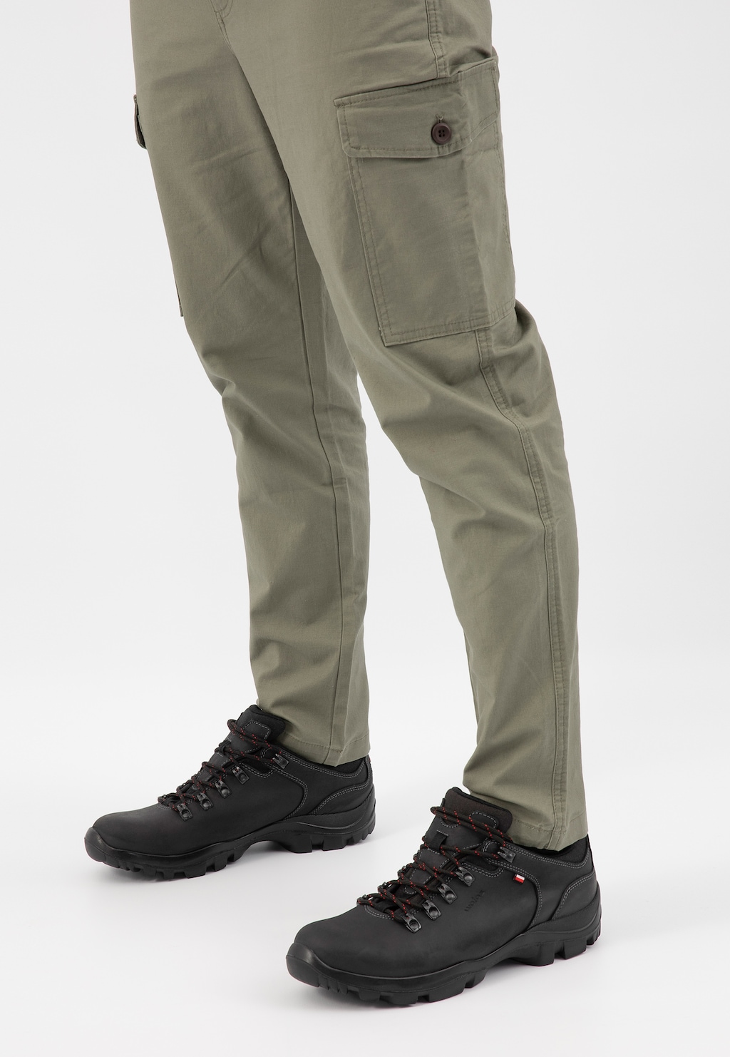 Czarne męskie półbuty Wojas model 9377-91 zestawione z beżowymi spodniami typu cargo. Widok z boku ukazuje solidną konstrukcję butów trekkingowych z czerwonymi akcentami sznurówek.