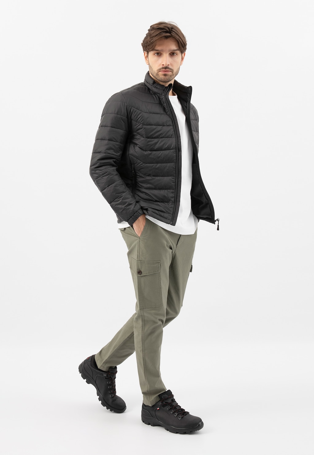 Model prezentuje czarne męskie półbuty Wojas 9377-91 w stylizacji z czarną pikowaną kurtką, białym t-shirtem i oliwkowymi spodniami cargo.