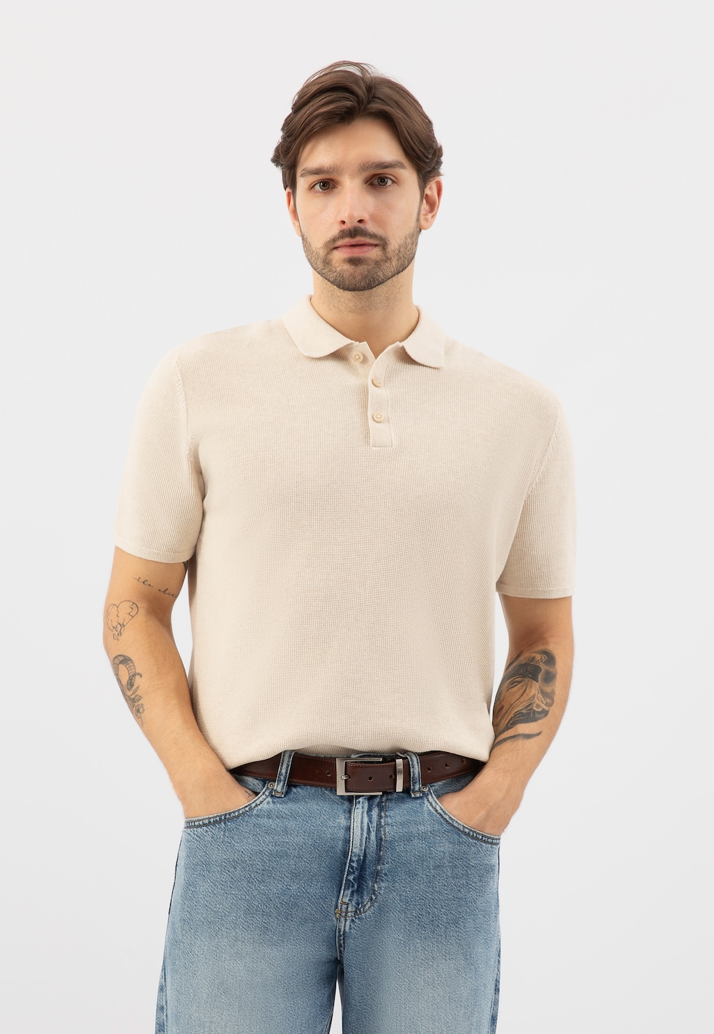 Mężczyzna w kremowej koszulce polo i jeansach, prezentujący skórzany brązowy pasek męski Wojas model 7980-52, elegancko dopełniający casualową stylizację.