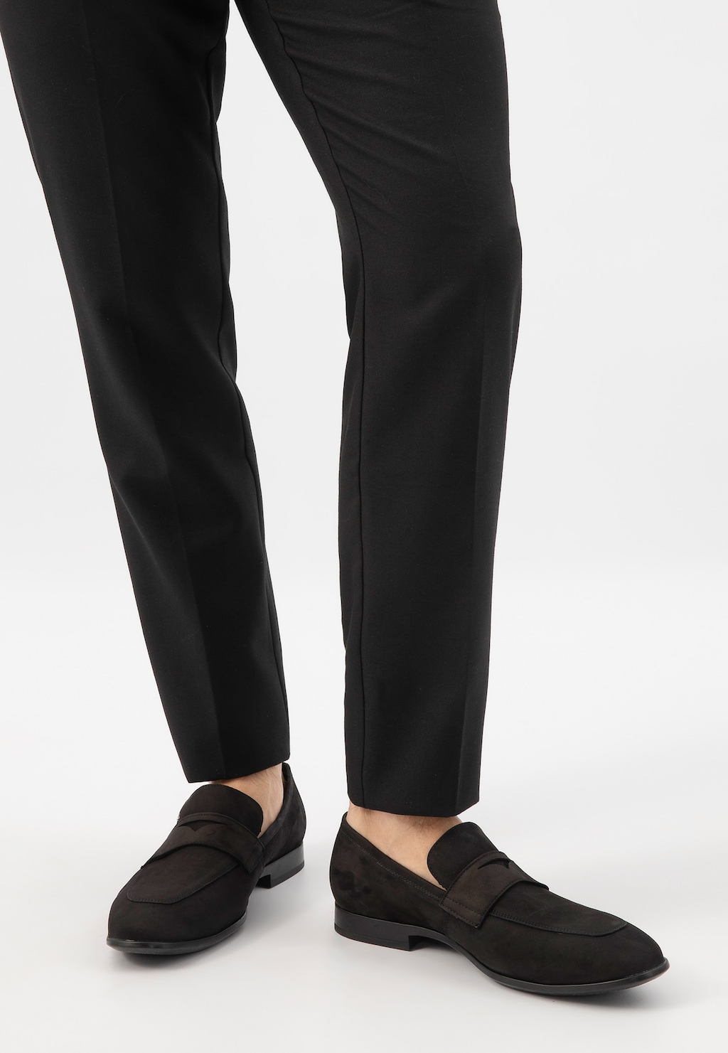 Czarne loafersy męskie Wojas model 10196-21 wykonane z nubuku, prezentowane na nogach w czarnych eleganckich spodniach. Widok z perspektywy frontalnej, ukazujący stylowy, klasyczny design butów.