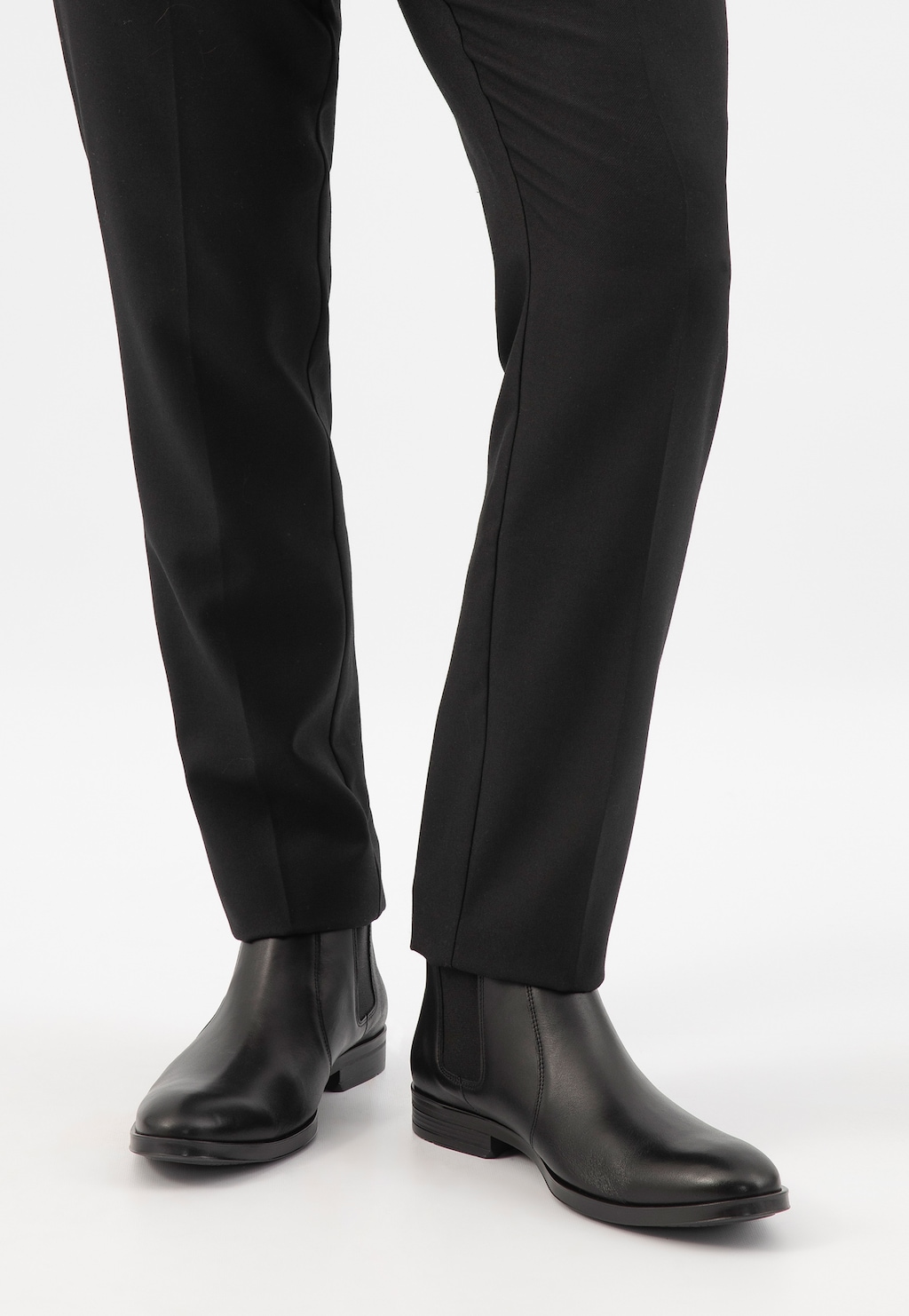 Eleganckie czarne sztyblety męskie Wojas model 20003-50 ze skóry licowej, widoczne na nogach w czarnych spodniach garniturowych, prezentujące klasyczny, biznesowy styl.