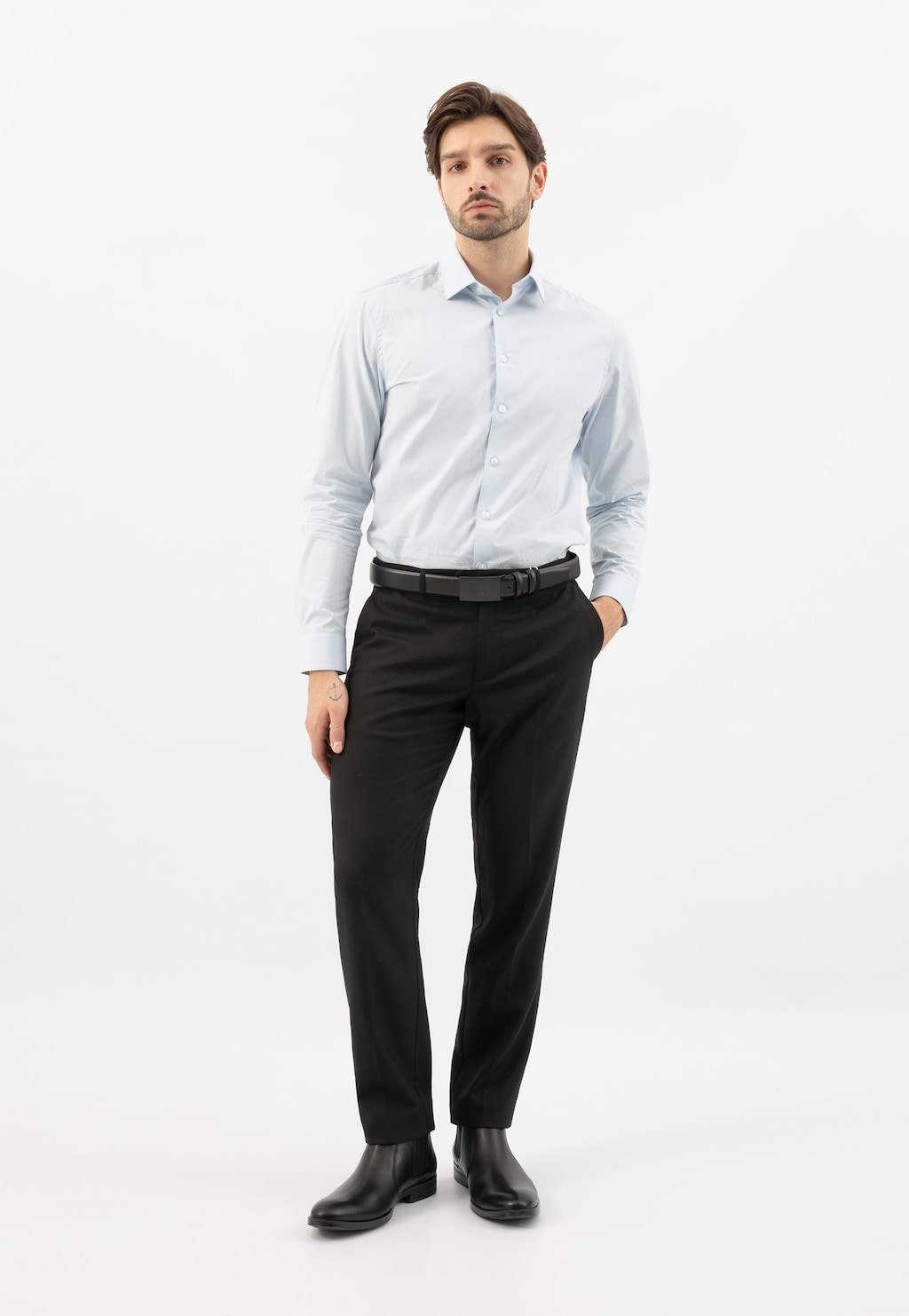 Elegancki mężczyzna w jasnej koszuli i czarnych spodniach, prezentujący czarne sztyblety Wojas model 20003-50 ze skóry licowej, widoczne na nogach w klasycznym biznesowym stroju.