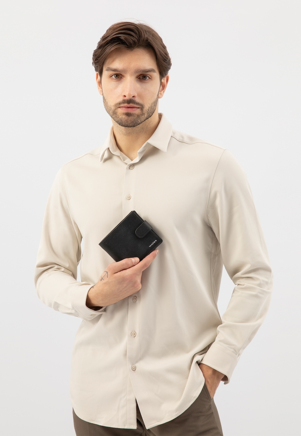 Elegancki czarny portfel męski Wojas model 91005-51 ze skóry licowej prezentowany w dłoni osoby ubranej w jasną koszulę.