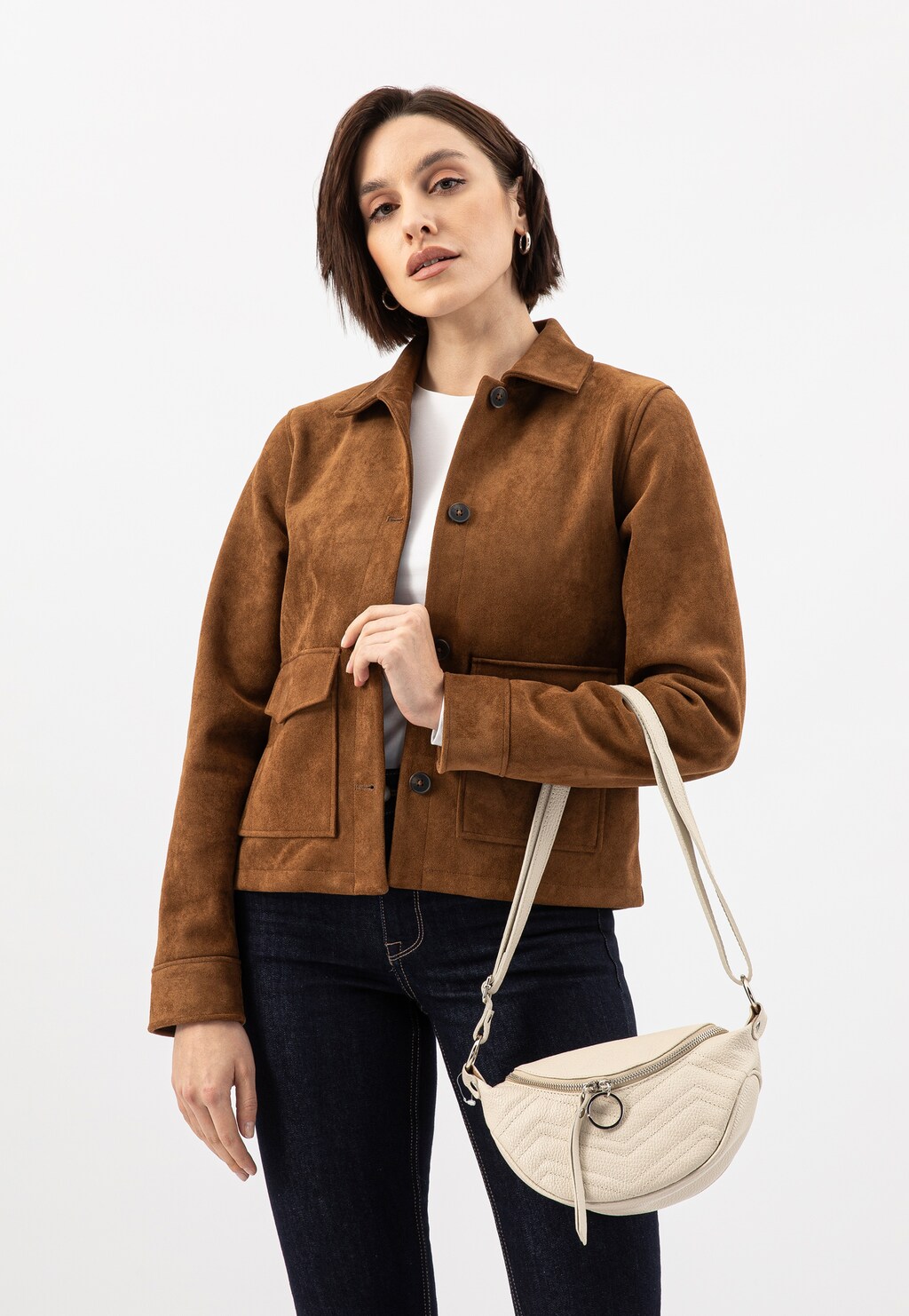 Modelka w brązowej zamszowej kurtce i ciemnych jeansach, prezentująca beżową pikowaną saszetkę damską Wojas 80093-54 ze skóry licowej zawieszoną na ramieniu.