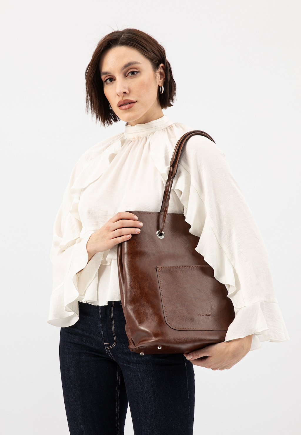 Elegancka brązowa torebka Wojas model 80019-52 z zewnętrzną kieszenią, prezentowana na ramię osoby w białej bluzce z falbanami i granatowych jeansach.