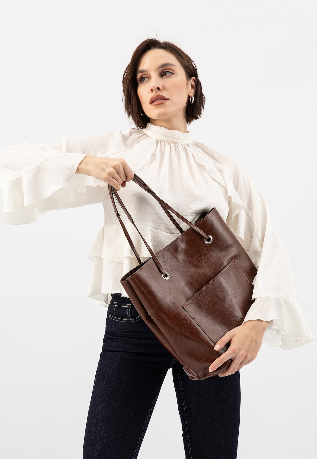 Elegancka brązowa torebka Wojas model 80019-52 z zewnętrzną kieszenią, trzymana przez osobę w białej bluzce z falbanami i ciemnych jeansach.